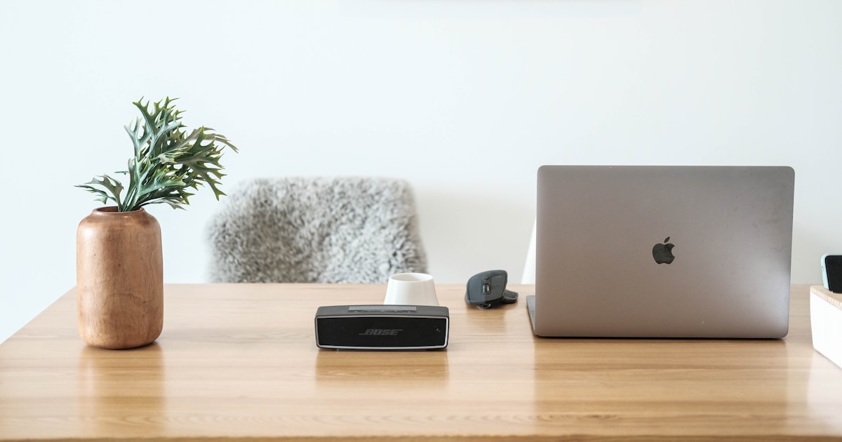 A MacBook open on a warm wooden desk