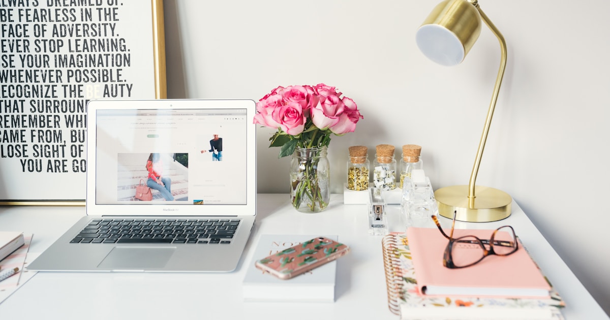 A tidy desk workspace with a MacBook and neatly stacked notebooks